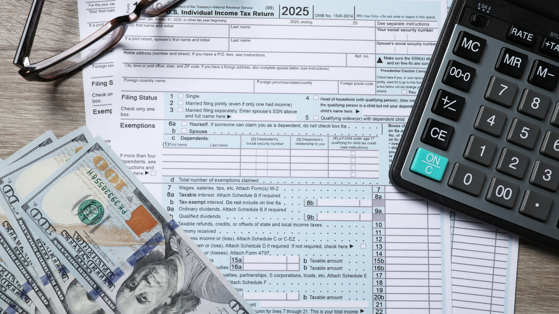 2025 U.S. Individual Income Tax Return form with glasses, cash, and a calculator on a surface.