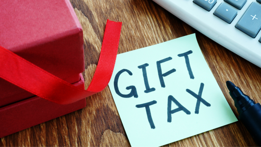 Red gift box with a note that reads 'GIFT TAX' next to a calculator and a black pen.