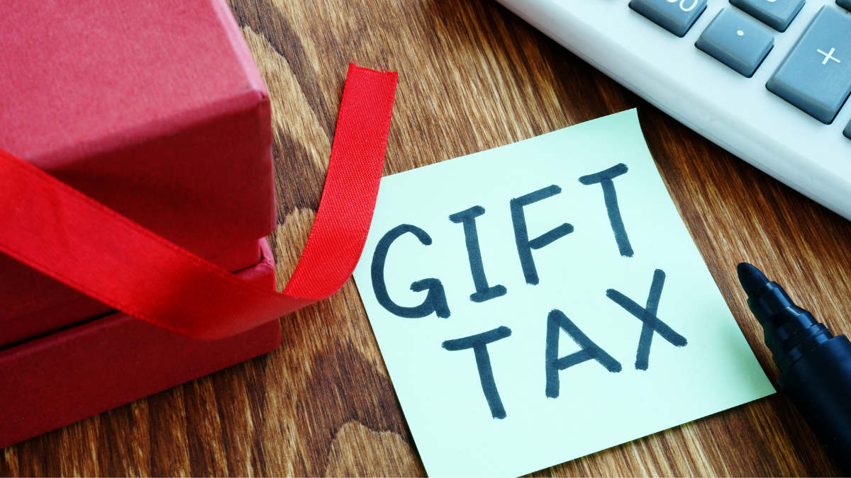 Red gift box with a note that reads 'GIFT TAX' next to a calculator and a black pen.